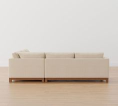 a couch sitting on top of a hard wood floor next to a white wall in an empty room