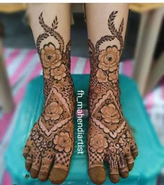 the legs and feet of a woman with henna tattoos on their hands, both decorated with flowers