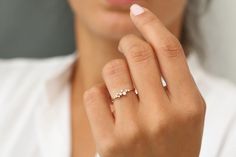 a woman wearing a gold ring with three small diamonds on the middle of her finger