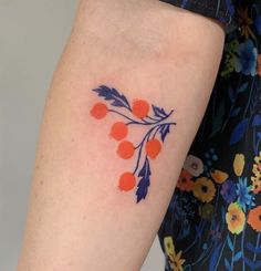 a woman's arm with an orange and blue flower tattoo on the left forearm