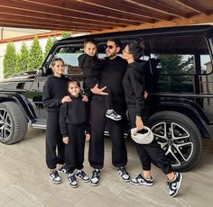 the family is posing in front of their vehicle