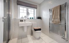 a bathroom with a toilet, sink and towel rack on the wall next to the window