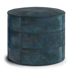 a round blue leather ottoman sitting on top of a white floor