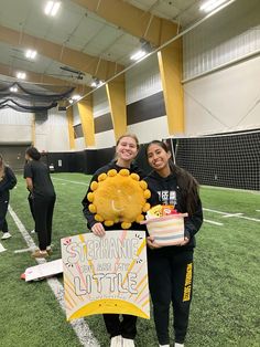 two girls standing on a football field holding cakes