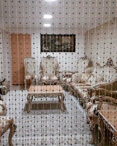 a living room filled with lots of furniture covered in white fabric and beaded curtains