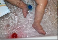 a baby laying in a bath tub next to a bottle of toothpaste and soap