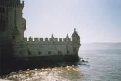 an old castle sitting on top of a cliff next to the ocean in front of a body of water