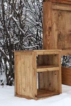 two wooden boxes sitting in the snow next to trees