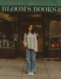 a woman standing in front of bloom's books and gifts store with her hands in her pockets