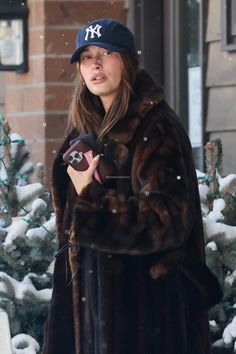 a woman in a fur coat and hat walking down the street