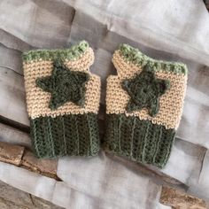 two green and white knitted mittens sitting on top of a piece of wood