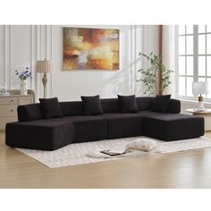 a large black couch sitting on top of a white rug in a living room next to a window