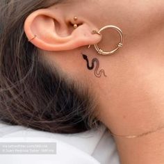 a woman with a tattoo on her neck and behind the ear is a small snake