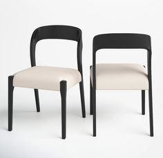 two black and white chairs sitting next to each other on a white surface with no one in it