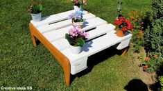 a table made out of an old pallet is sitting in the grass with potted flowers on it