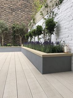 an outdoor area with wooden floors and plants on the wall, along with white brick walls