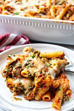 a white plate topped with lasagna covered in cheese and sauce next to a casserole dish