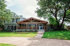 a house with trees in the front yard and grass on the side walk leading to it