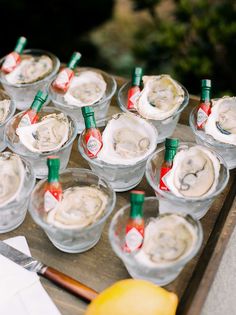 there are many small cups with ice cream in them on the wooden tray next to some lemons