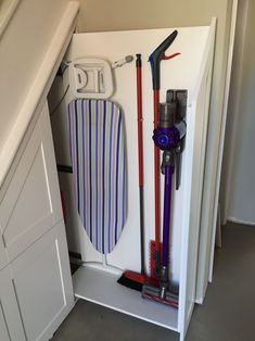 an under the stairs storage area with cleaning supplies and vacuum cleaners on top of it