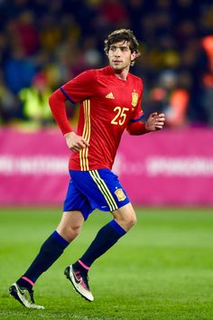 a soccer player in red and blue runs with the ball during a game against spain