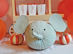 an elephant pillow sitting on top of a table next to some pumpkins and balloons