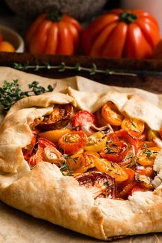 a pizza sitting on top of a wooden cutting board next to tomatoes and other vegetables