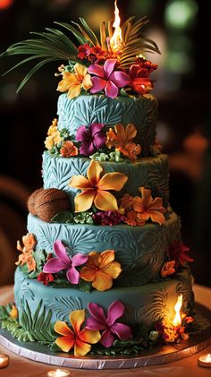 a three tiered cake with flowers and candles on the table in front of it