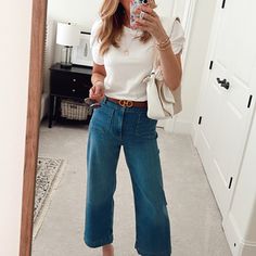 a woman taking a selfie in the mirror wearing high waist jeans and a white t - shirt