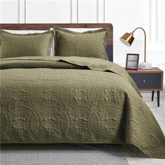 a bed with green bedspread and pillows