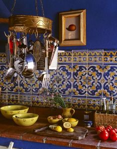 a kitchen counter with bowls, utensils and other items hanging from the ceiling