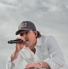 a man holding a microphone in his right hand and singing into the microphone with both hands