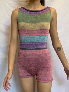 a woman with her hands in her pockets wearing a multicolored striped bodysuit