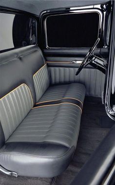 the interior of an old fashioned car with black leather and yellow stitching on it