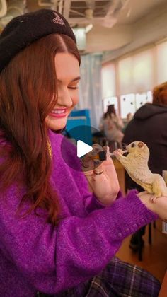 a woman holding an owl in her hand and looking at it's own reflection