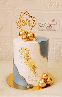 a white and blue cake with gold decorations