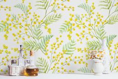 yellow flowers and green leaves on a white wallpapered room with bottles, jars and vases