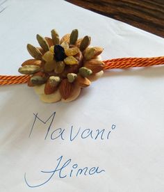 a piece of paper with an orange string attached to it and some nuts on top