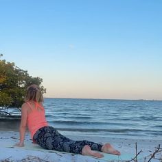 a woman sitting on top of a surfboard next to the ocean