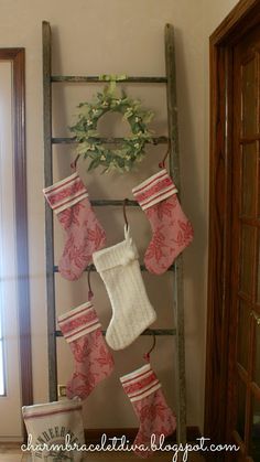 stockings hung on an old ladder in the corner of a room with a wreath and potted plant