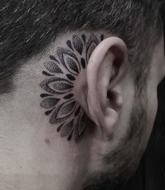 a man with a tattoo on his ear and behind the ear is a black flower