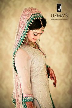 a woman in a white and green bridal outfit with her hands on her hips