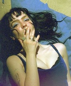 a woman laying on top of a bed with her hands in her mouth and eyes closed