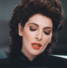 a woman with dark hair and orange lipstick