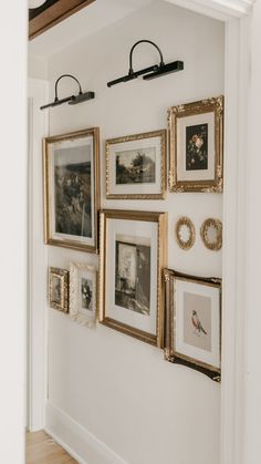 a white wall with many pictures hanging on it's sides and gold frames above them