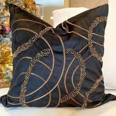 a black and gold pillow sitting on top of a white couch next to a christmas tree