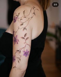 a woman wearing a black dress with purple flowers on her arm and shoulder tattoo design