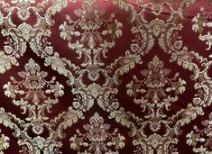 a red and gold brocaded fabric with white flowers on the bottom, in an ornate pattern