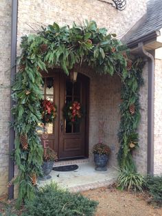 the front door is decorated with greenery and pine cones