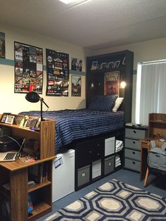 a dorm room with a bed, desk and computer on top of the dressers